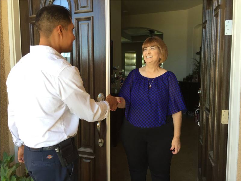 Dan's Pest Management technician shaking hands with a happy homeowner at the front door after completing pest control service in Bakersfield, CA.